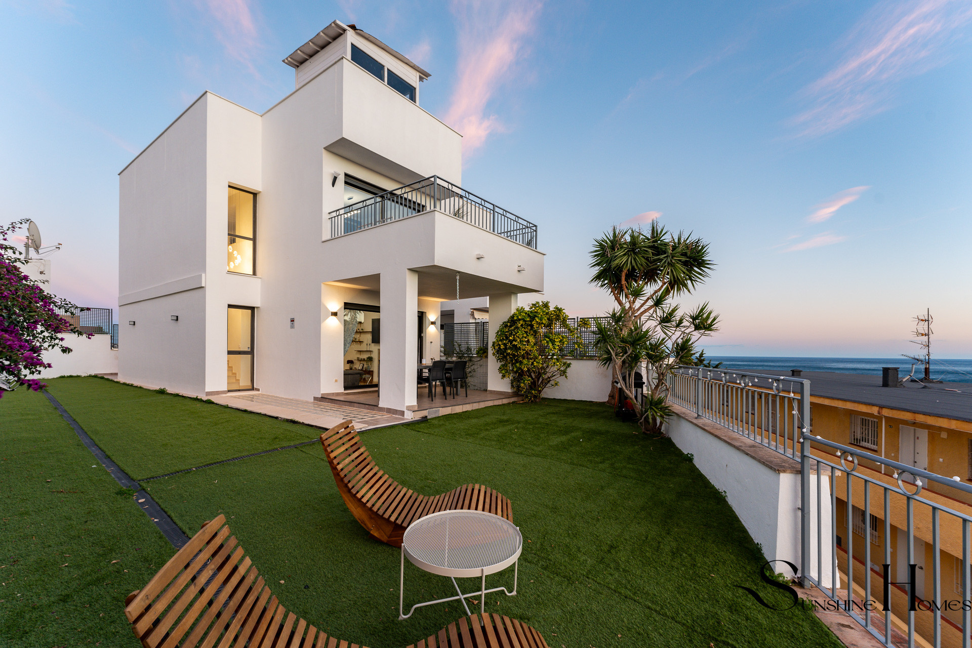 White townhouse with a lawn terrace and sea view at sunset